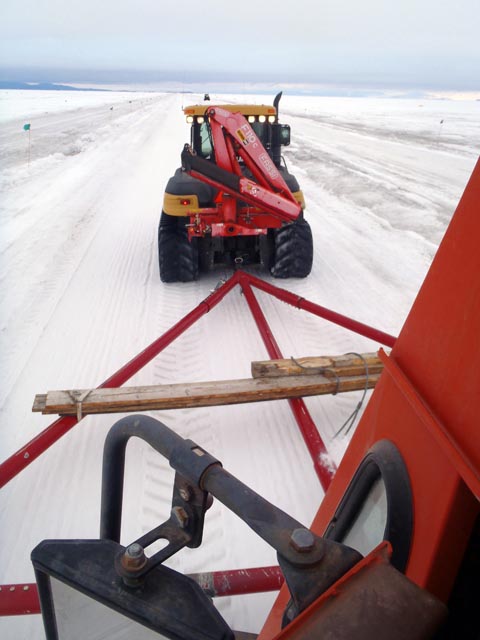 A tractor pulls a sled across snow.