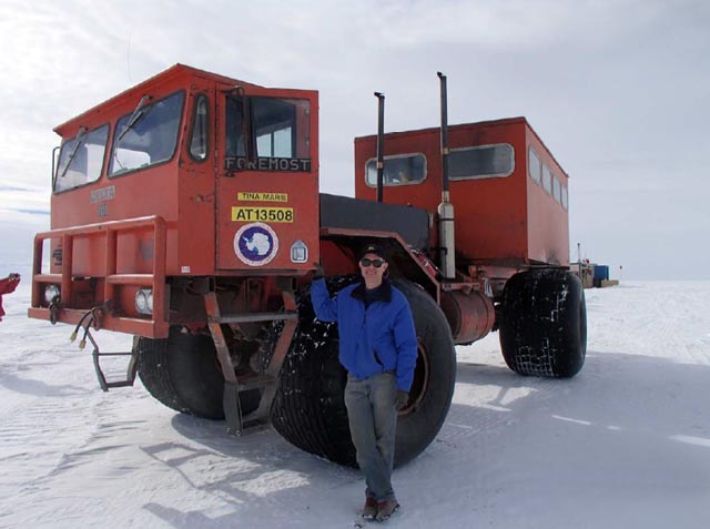Man stands next to large vehicle.