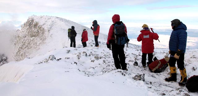 People stand on snowy ridge.