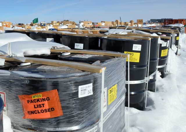 Barrels and other items covered by snow outside.