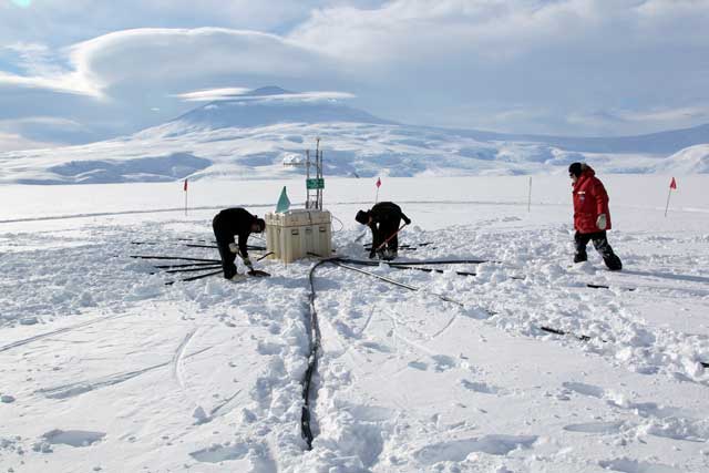 People work on box in snowy area.