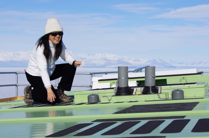 Woman kneels on roof of green building.