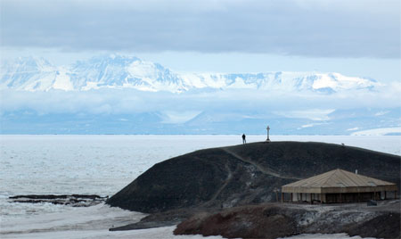 Small building near end of a peninsula surrounded by ice.