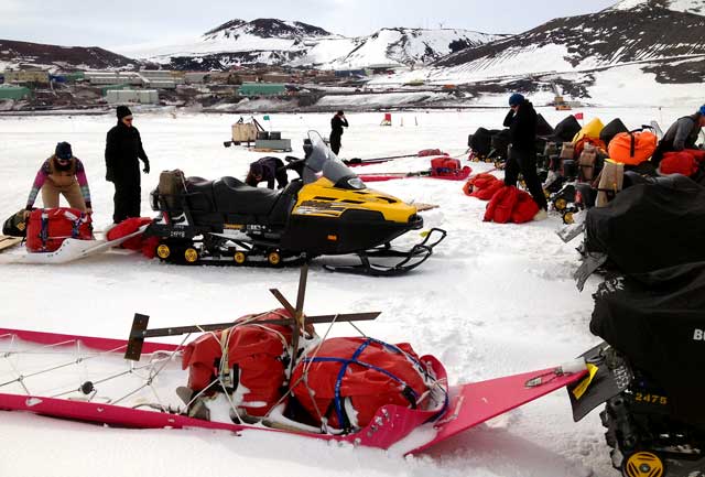 People load sleds for snowmobiles.