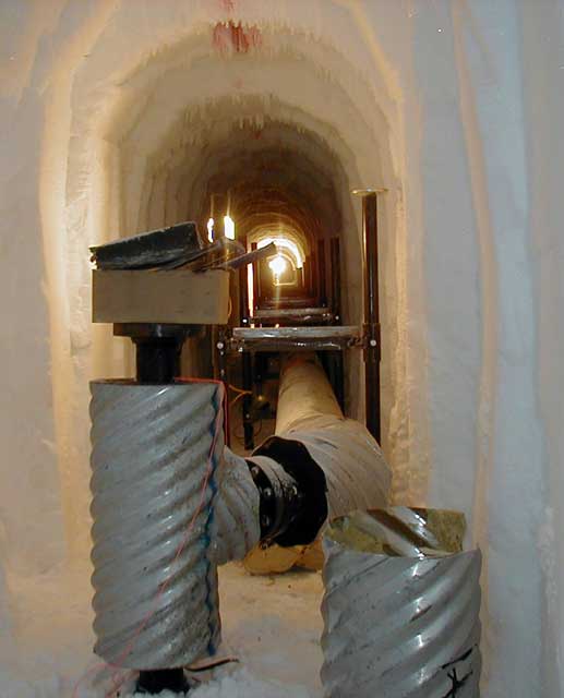 Large pipes run through tunnel of ice.