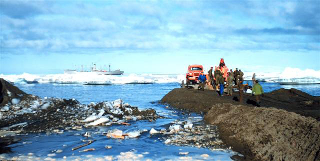 People and vechile on spit of land.