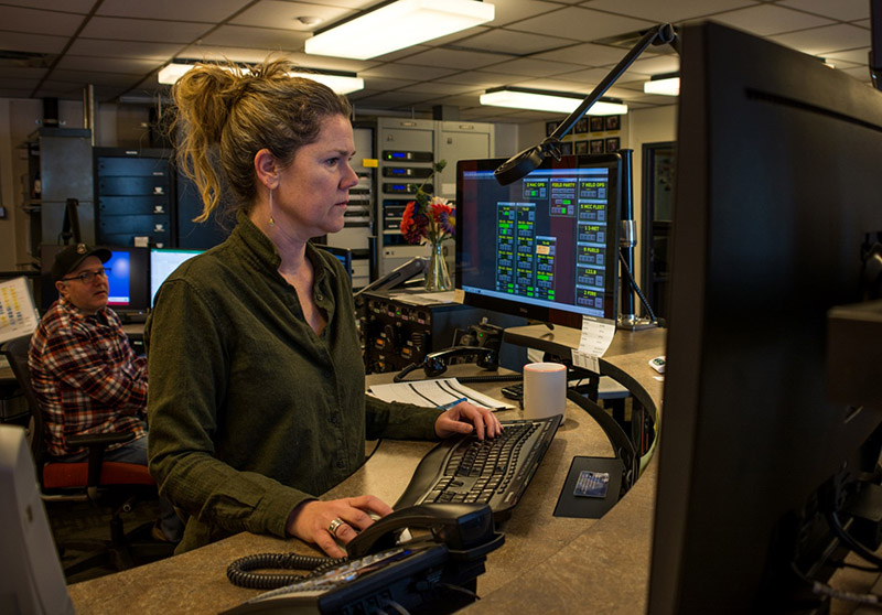 Communications operator Rebecca Ricards (foreground) calls up field camp information at the MacOps control console. Josh Young looks on