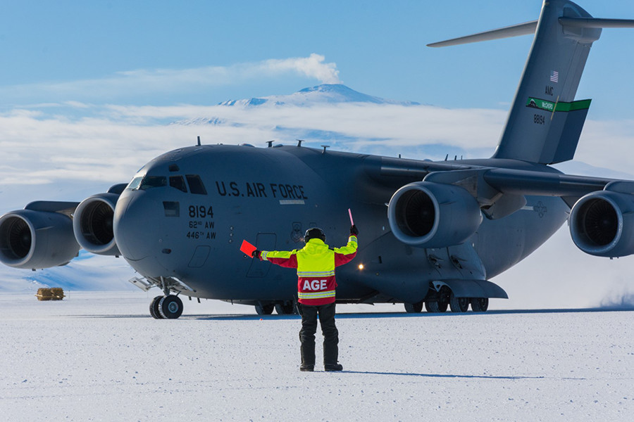 A member of ground crew directs a C-17 as it performs a series of test maneuvers