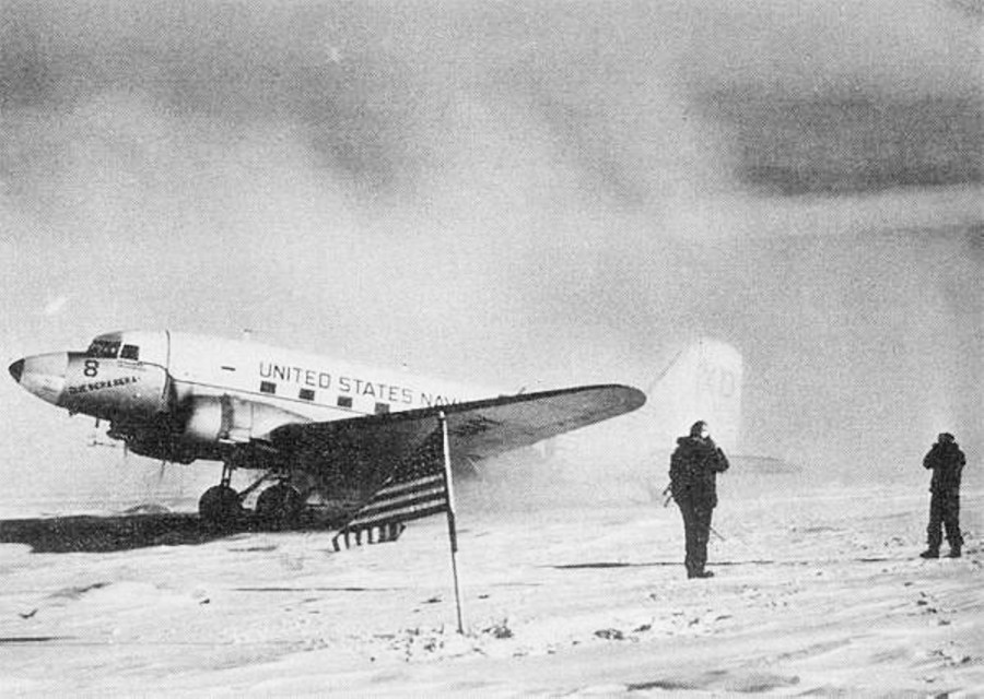 The R4D-5 Skytrain Que Sera Sera is parked at the South Pole behind the American flag after landing at the South Pole in 1956