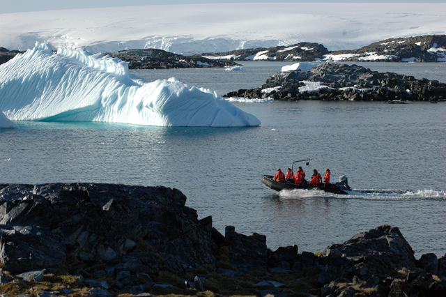 People navigate boat through icebergs.