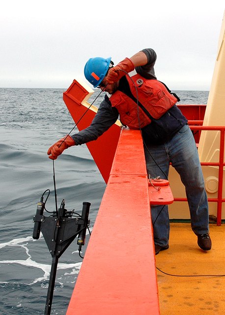 Scientist lowers instrument into the water.