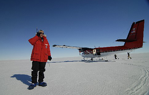 Man standing on ice with plane in background.