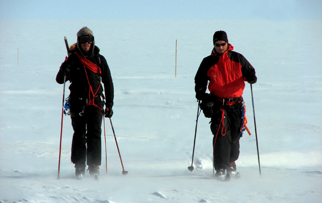 Two men ski on snow and ice.