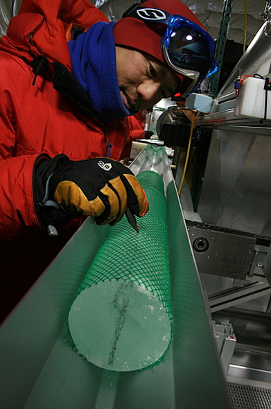 Man draws on ice core wrapped in green webbing.