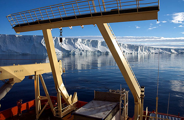 Stern of a ship with ice shelf in background.