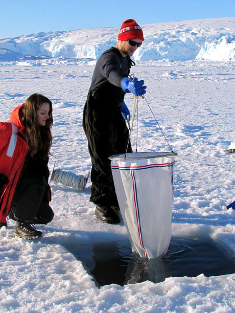 Two people put dip net in water.