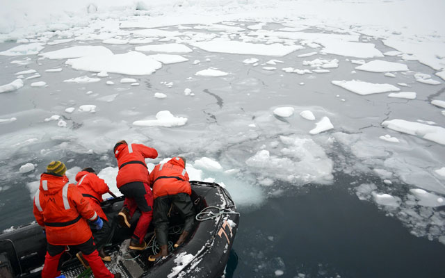 Boat moves through ice-covered sea.