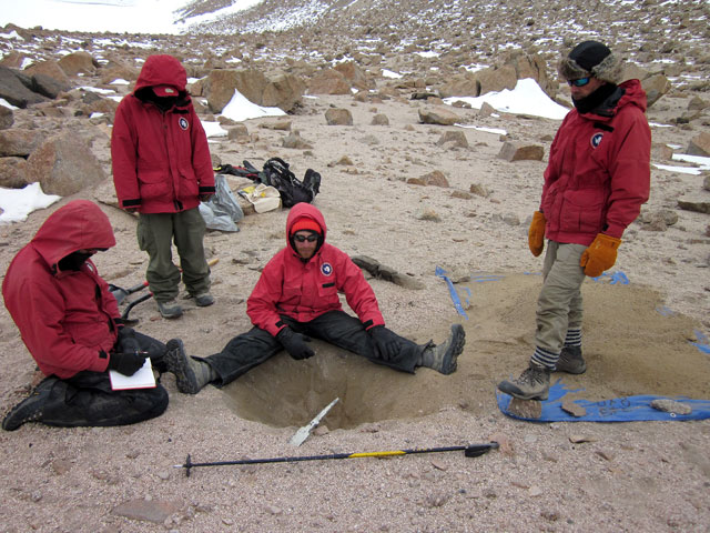 People gather around a pit.