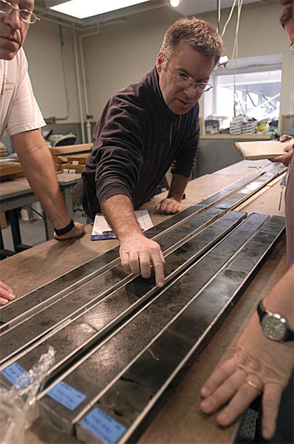 People examine item on a table.