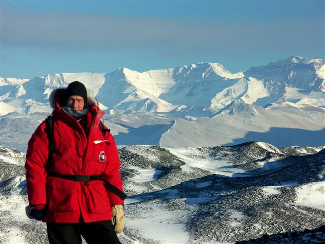 Person stands in front of mountain range.