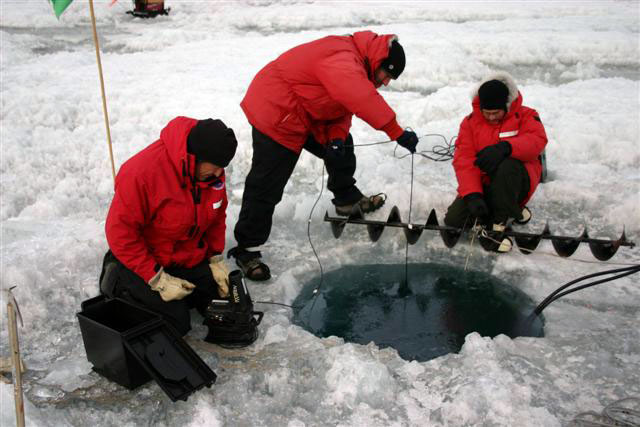 People drill a hole through ice.