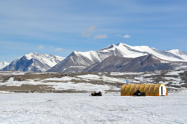 Yellow tent and snowmobiles on ice.