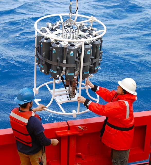 Two people deploy an instrument into the ocean.