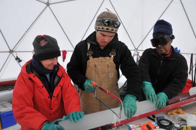 Three people examine an ice core.