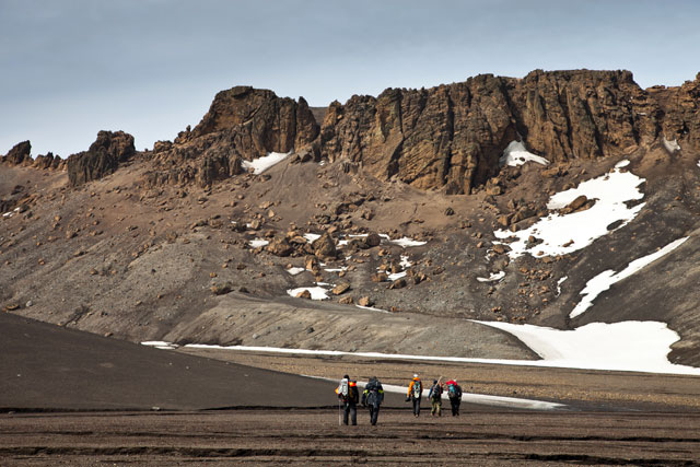 People hike in rugged terrain.
