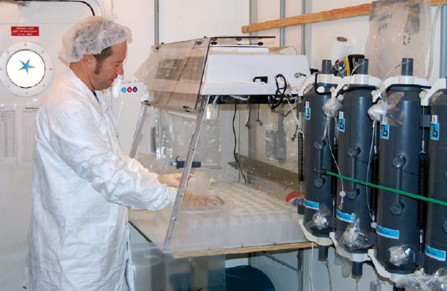 Man in sterile garb works in a lab.
