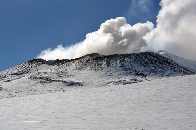 Smoke rises from mouth of volcano.