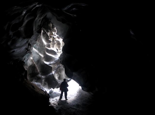 A person's silhouette at a cave entrance.