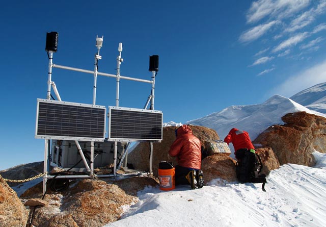 Two people in heavy coats set up instrument.