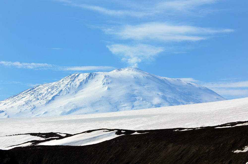 Smoke rises from snow-covered volcano.
