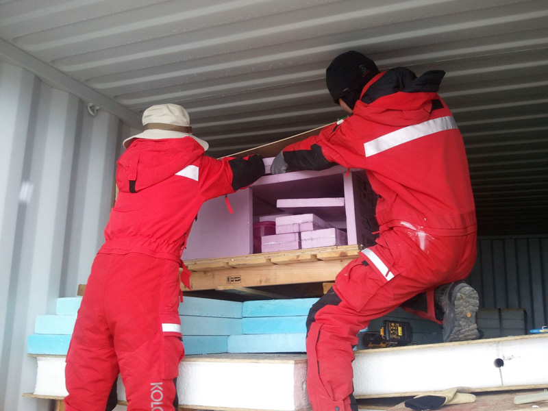 Workers at the Korean Station Jang Bogo unload components to the CosRay experiment after being shipped to their station from winter storage in Australia.