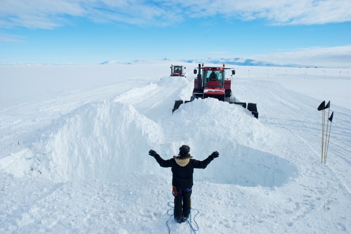 Tractor pushes snow toward hole.