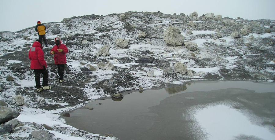Scientists survey unusual sulfate formations near a small pond by the Lewis Cliff Ice Tongue.