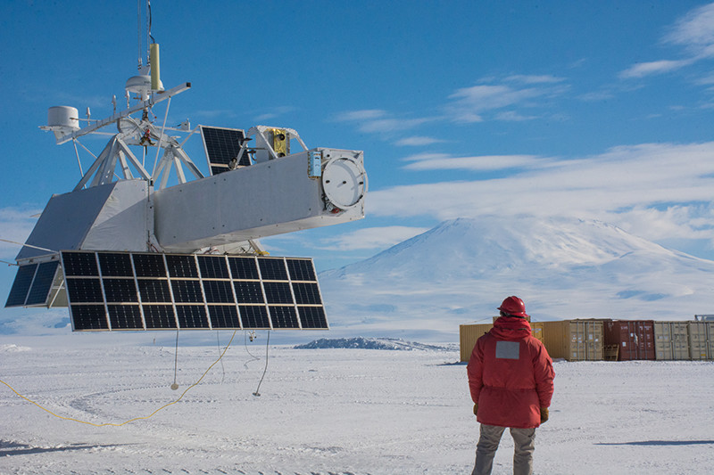 The GRIPS scientific payload hangs suspended over the frozen surface of McMurdo Station’s Long Duration Balloon field as one of launch crew looks on