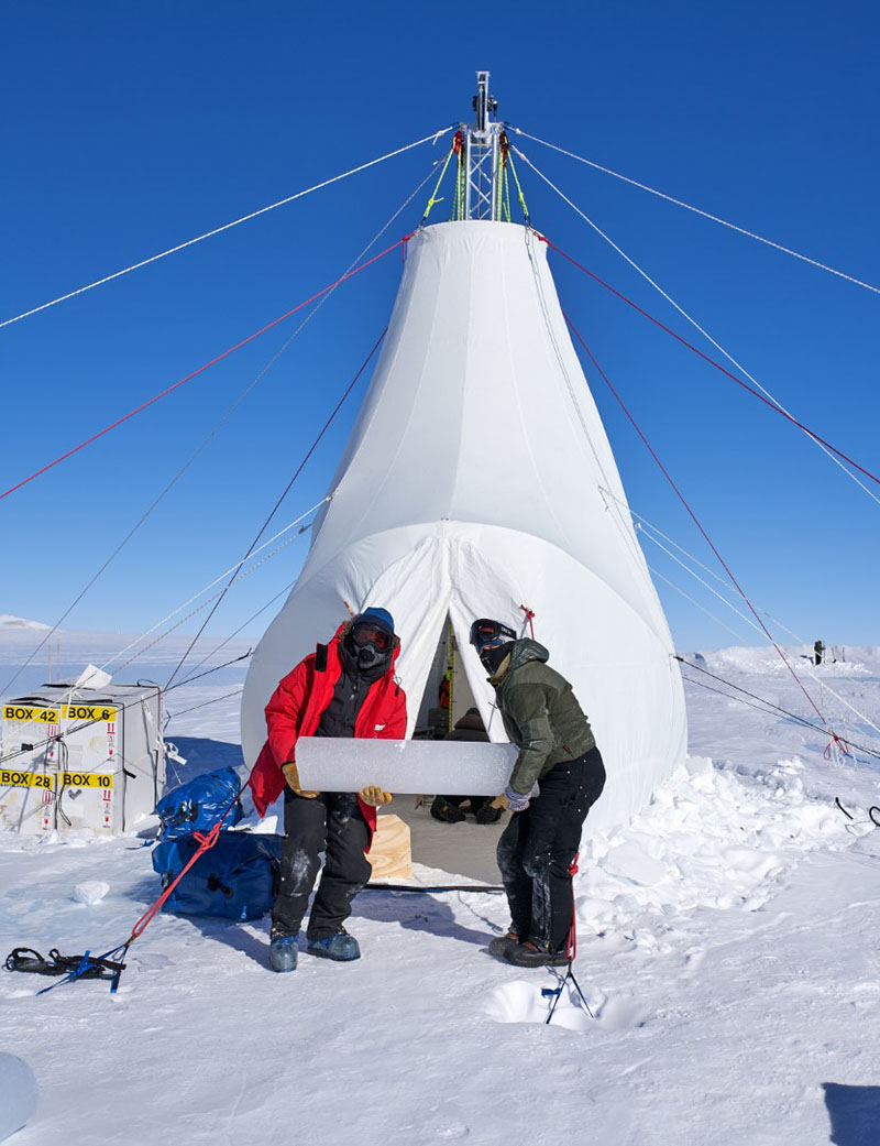 Austin Carter (left) and Elizabeth Morton carry out an ice core from the drill tent