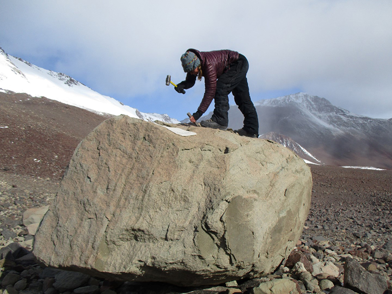 Allie Belter chips off a sample of a large stone that was deposited thousands or millions of years ago by now-receded glaciers
