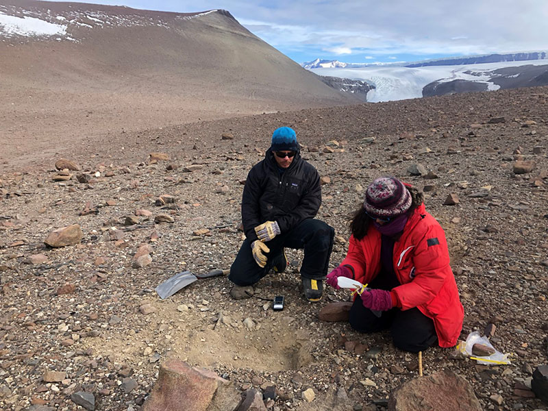 Melisa Diaz (right) collects a soil sample as mountaineer Geoff Shellens takes a GPS coordinates