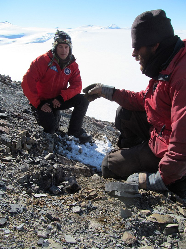 Erik Gulbranson and mountaineer Jonathan Hayden look at a small fossil tree