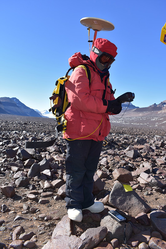 Kate Swanger hauls a GPS unit to get precise location data for each rock sample they collected.