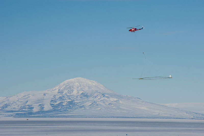 With SkyTEM in tow, a Bell 212 helicopter flies over the sea ice of McMurdo Sound on a practice run
