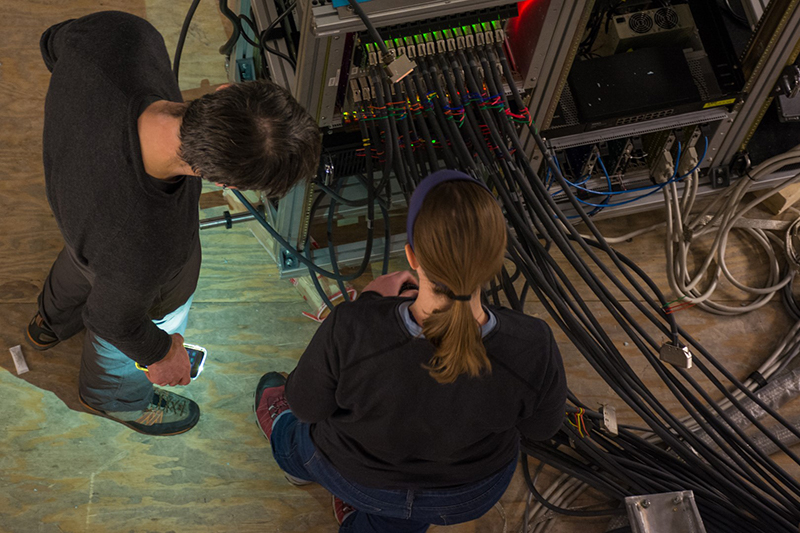Matt Dobbs (left) and Amy Bender inspect the cables that carry the data from the telescope's detector to the hard drives that store the collected data