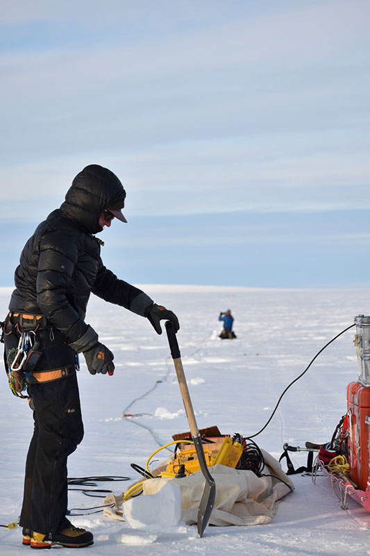 Glaciologist Kiya Riverman prepares to install seismic listening devices in the snow to map the terrain far below the ice.