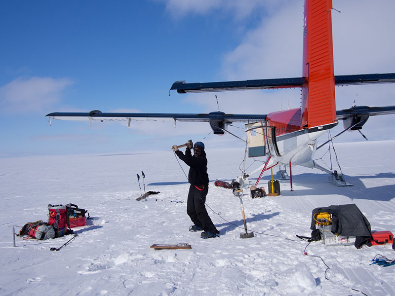 Glaciologist Sridhar Anandakrishnan hits the surface of the ice with a hammer to send seismic waves through the ground and calibrate the MELT team's instruments.