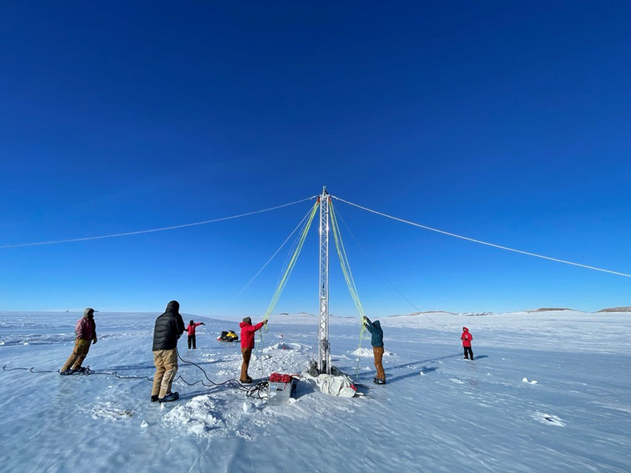 A team sets up a drill tower on an Antarctic landscape.