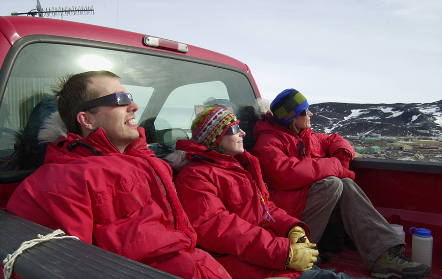 U.S. Antarctic Program participants Joe Harrigan, Katie Burke and Allisha Ochs watch the solar eclipse above McMurdo Station on November 24, 2003.