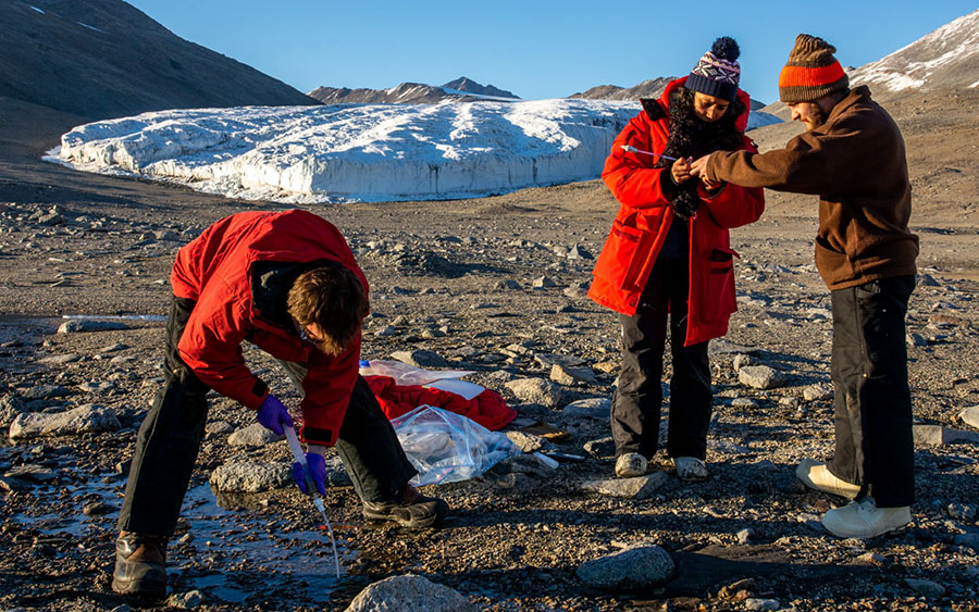 Chris Gardner (left) takes a water sample from a glacial stream in Miers Valley while Melisa Diaz (center) and Adolfo Calero examine a sampling pipette.